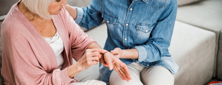 An elderly woman on a sofa having a wrist injury examined