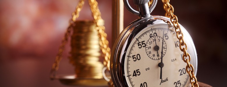 Old-fashioned scales weighting a stack of coins and a stopwatch