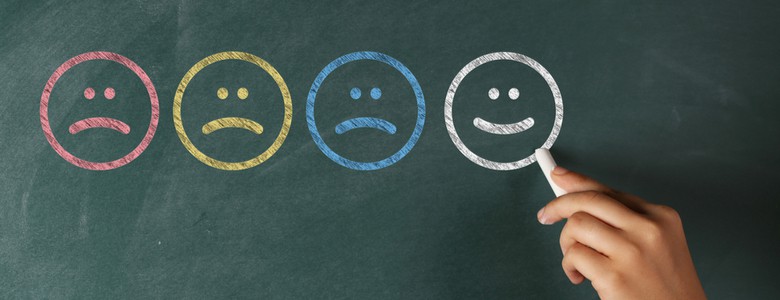 Different coloured faces drawn on a blackboard with a smiley face last