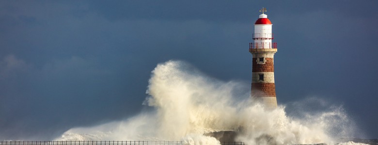waves crashing against a lighthouse in a storm