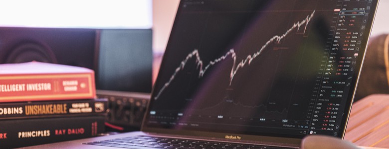 A laptop on a desk showing a rising line graph