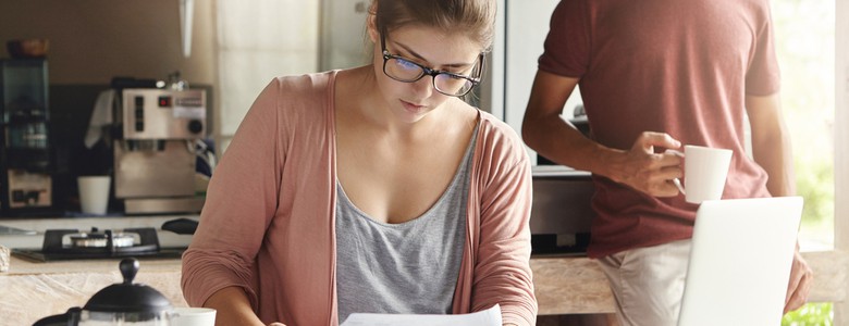 A woman sat at a kitchen table with a laptop