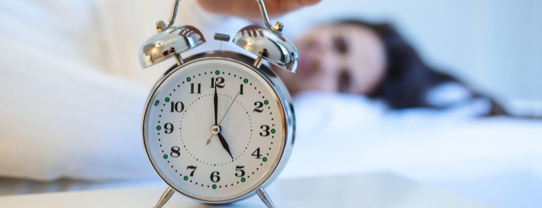 A woman reaching for her alarm clock