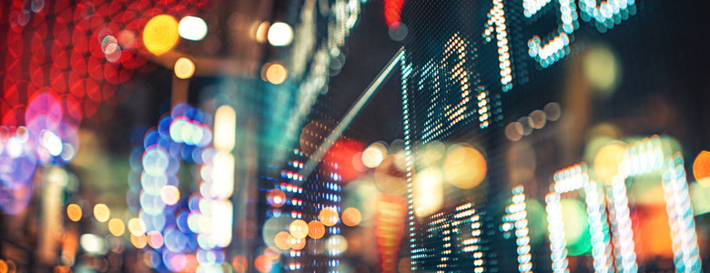 A blurred view of stock market figures on a neon-lit street