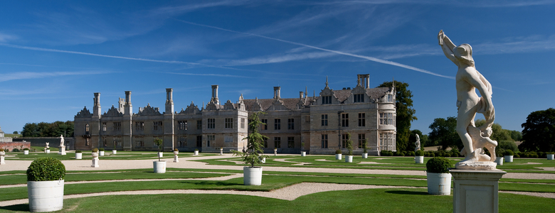 A large lawn with statues and a stately home