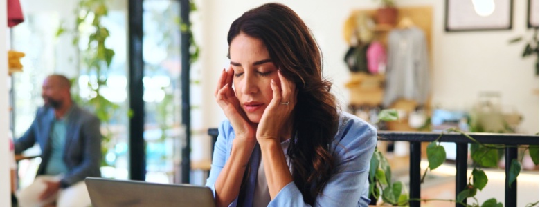 A woman at her laptop struggling to focus.